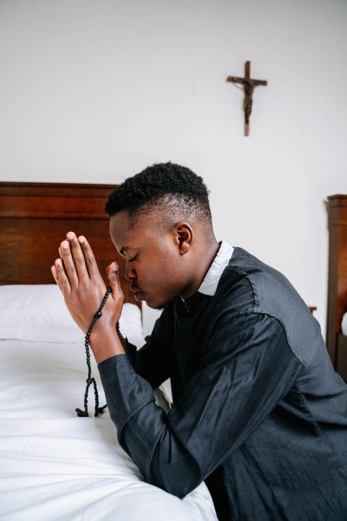 man in black dress shirt kneeling on bed